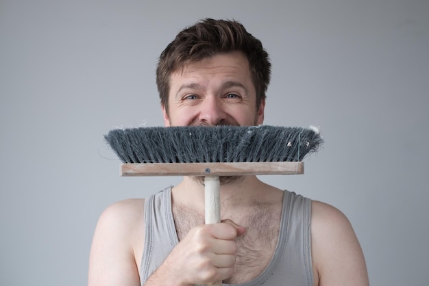 Tired young man with mop on white background