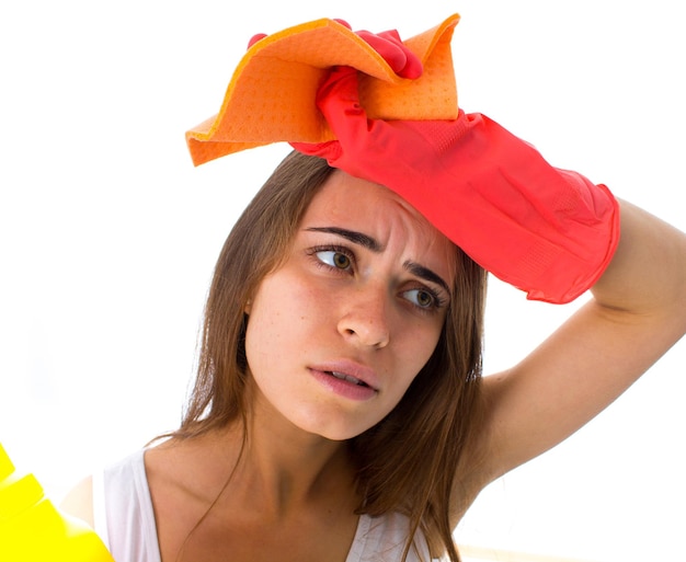 Tired young woman in white shirt and red gloves holding duster and detergents on white background