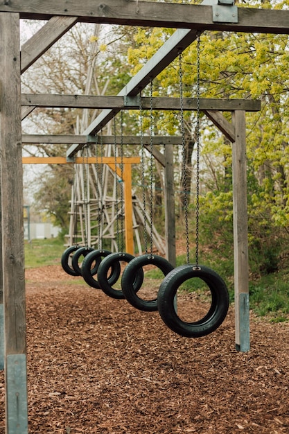 Tires from the wheels hang on chains in the park on a sunny day