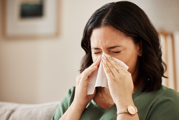 鼻を吹き飛ばす女性リビングルームでインフルエンザ風邪ハイフィーバーウイルス感染症を患っている女性アレルギーくしゃみをしている女性健康上のリスクを抱えている女性