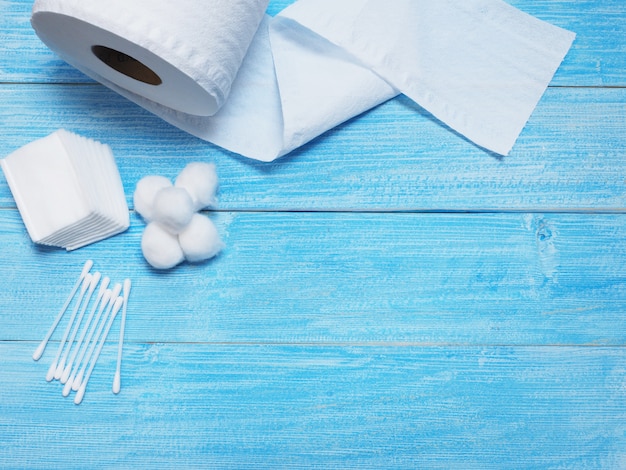 Tissue paper and cotton buds on wooden blue background.