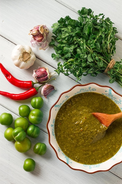 Tkemali sauce traditional Georgian cuisine green cherry plum on a white wooden table closeup rustic food background no people selective focus