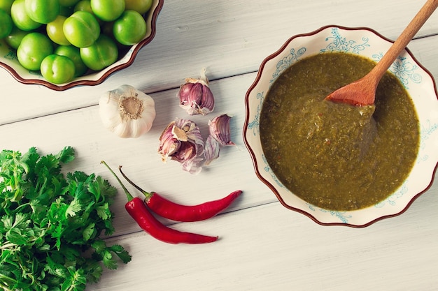 Tkemali sauce traditional Georgian cuisine green cherry plum on a white wooden table closeup rustic food background no people selective focus