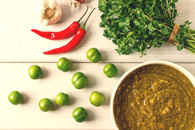 Tkemali sauce traditional Georgian cuisine green cherry plum on a white wooden table closeup rustic food background no people selective focus