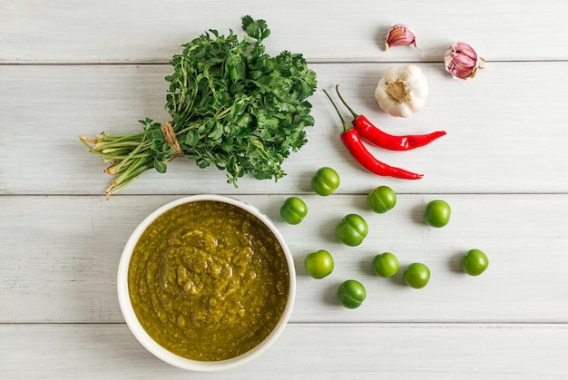 Tkemali sauce traditional Georgian cuisine green cherry plum on a white wooden table closeup rustic food background no people selective focus