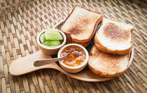 Toast bread served on wooden tray with sweet jam and lime homemade breakfast