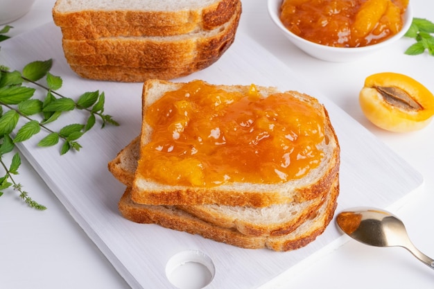 Toast brood met abrikozenjam en vers fruit met munt op witte houten tafel Lekker ontbijt