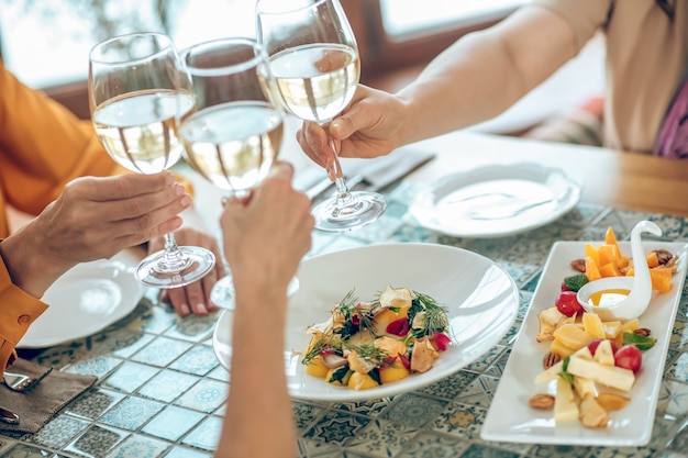 Toast. close up picture of galsses with wine in hands of friends