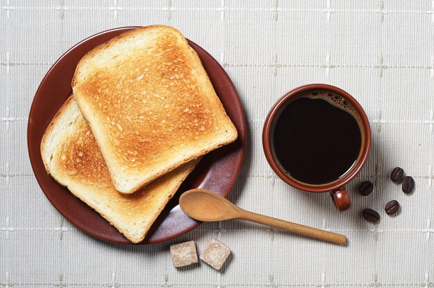 Toast and cup of hot coffee on tablecloth. Top view