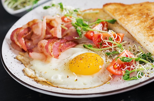 toast, ei, bacon en tomaten en microgreensalade.