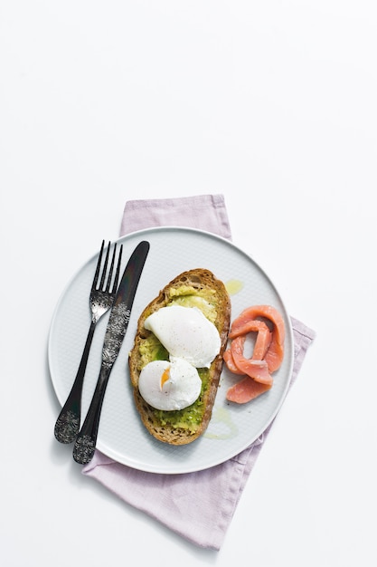 Toast met avocado, ei, zalm en zwart brood.