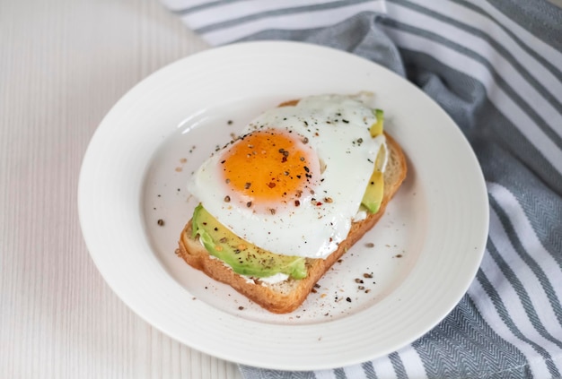 Foto toast met avocado op een witte plaat gemaakt van volkoren brood gebakken ei bovenaanzicht