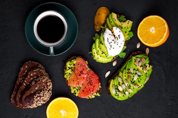 Toast met avocado, sesamzaadjes, grapefruit, sinaasappel, ei en koffie op een stenen achtergrond. heerlijk ontbijt met koffie en toast