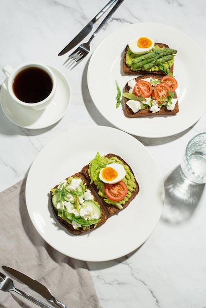 Toast met ei-avocado en andere groenten op een grijze achtergrond in een bord gezond ontbijt