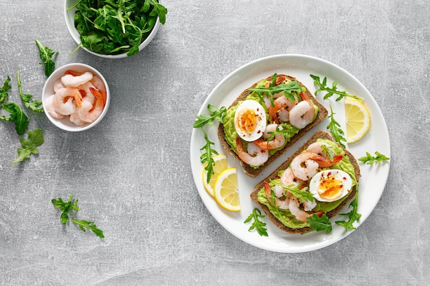 Toast met garnalen avocado guacomole rucola en gekookt ei bovenaanzicht