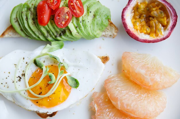 Toast met gebakken ei avocado en fruit voor het ontbijt