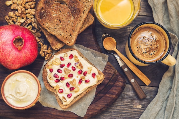 Toast met hummus, walnoten en granaatappel op rustieke houten. gezond ontbijt.