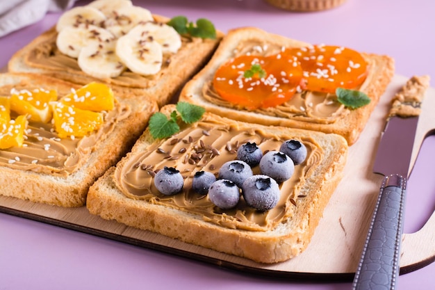 Toast met pindakaas, fruit, lijnzaad en sesamzaadjes op een snijplank