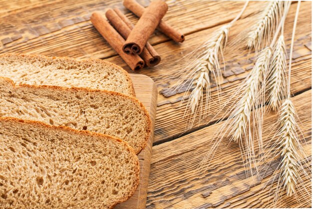 Toast op houten snijplank, kaneelstokjes en droge aartjes van tarwe op houten planken. Bovenaanzicht.