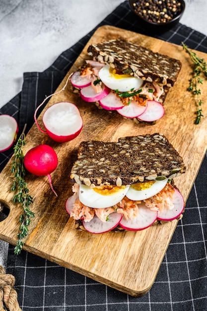 Toast van graanbrood met hete gerookte zalm, ei en radijs., Bovenaanzicht.