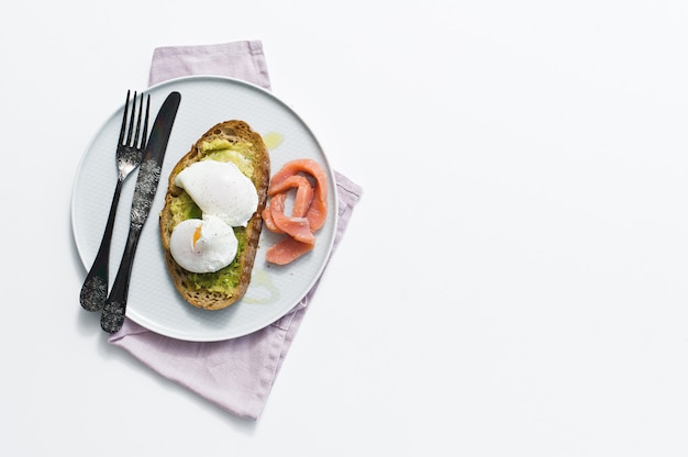 Toast with avocado, egg, salmon and black bread. 