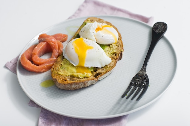 Toast with avocado, egg, salmon and black bread. 