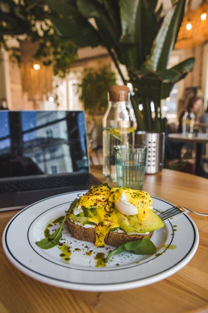 Toast with avocado and eggs on the plate in restaurant brown colors copy space