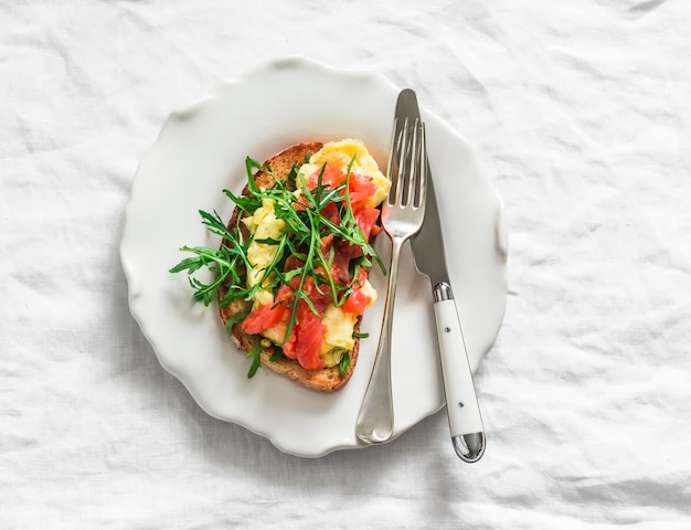 Toast with avocado omelette salmon and arugula on a light background top view Delicious breakfast snack tapas