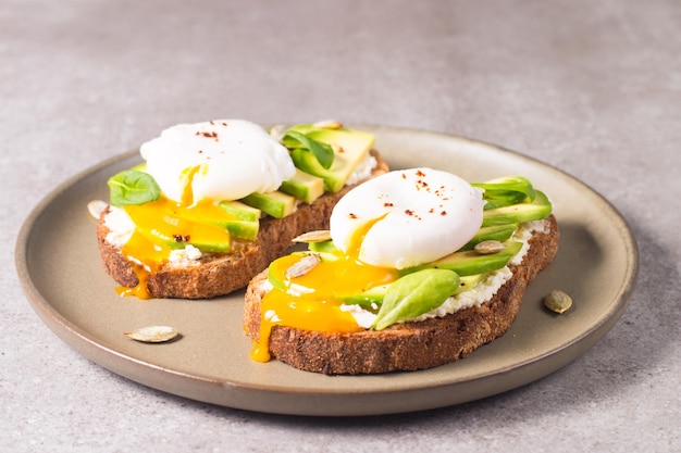 Toast with avocado, soft cream cheese, rye bread and poached Egg.