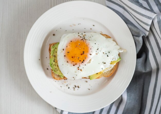 Foto tostare con l'avocado su un piatto bianco a base di uova fritte di pane integrale