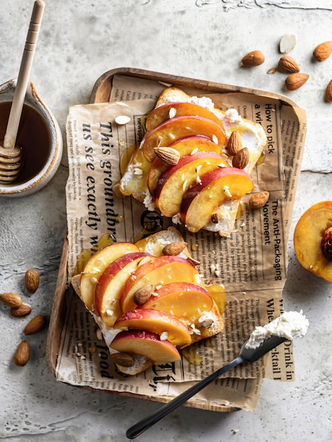 Toast with cream cheese fresh juicy peach almond and honey Healthy summer appetizer or snack