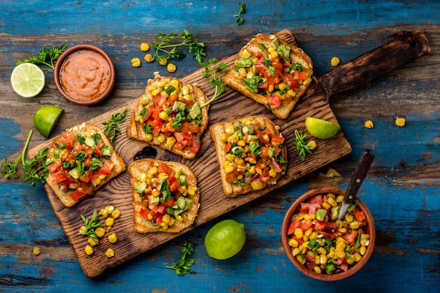 Toast with maize and vegetables on wooden board