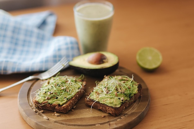 Toast with microgreens and guacamole on top Rye toasted bread on wooden board Healthy food at home Vegan food concept