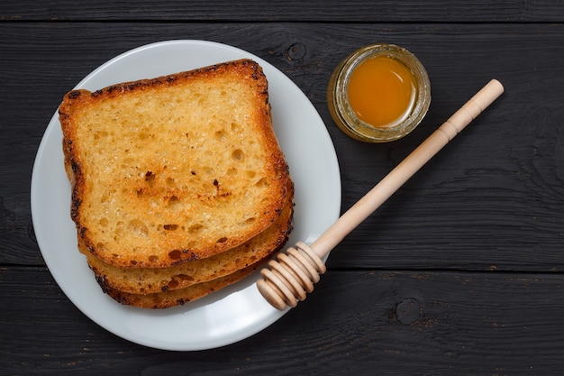 Toast with milk and a jar of honey on a black wooden background