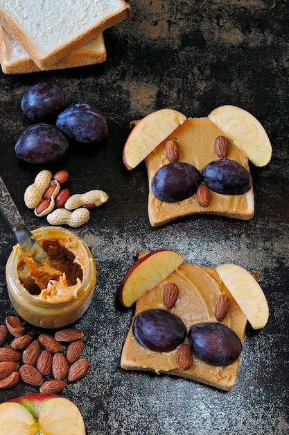 Toast with peanut butter in the form of animal faces. Funny animal face toasts with peanut butter, nuts and fruits.