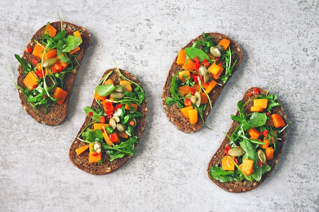 Toast with pumpkin and arugula. Open sandwiches with pumpkin. Healthy vegan toasts with greens and pumpkin. Autumnal snack. Bruschetta with arugula and pumpkin.