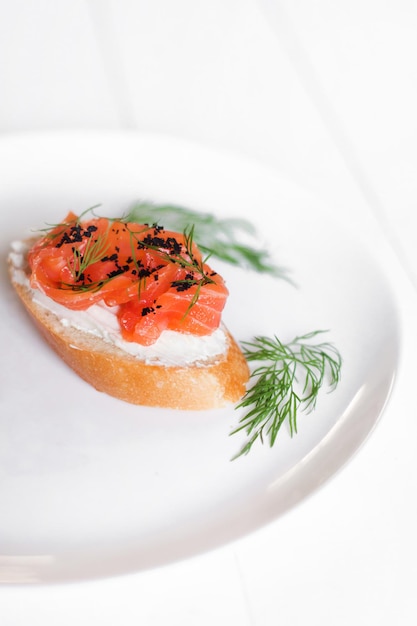 Toast with red fish and greens on a white plate