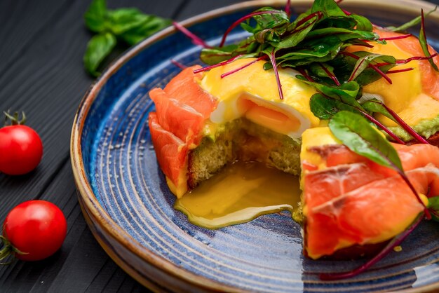 Toast with salmon, poached egg and avocado on a plate. Breakfast at the restaurant