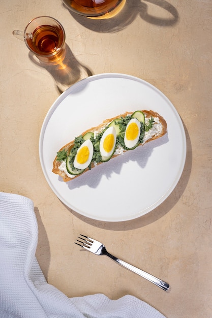 Toast with toasted bread soft-boiled eggs with yellow yolk and with herbs on white plate on light table