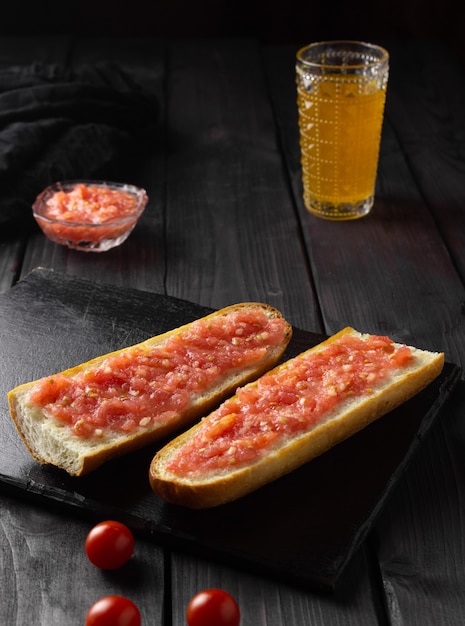 Toast with tomato, traditional Spanish breakfast. Olive oil, black background. Pan tumaka