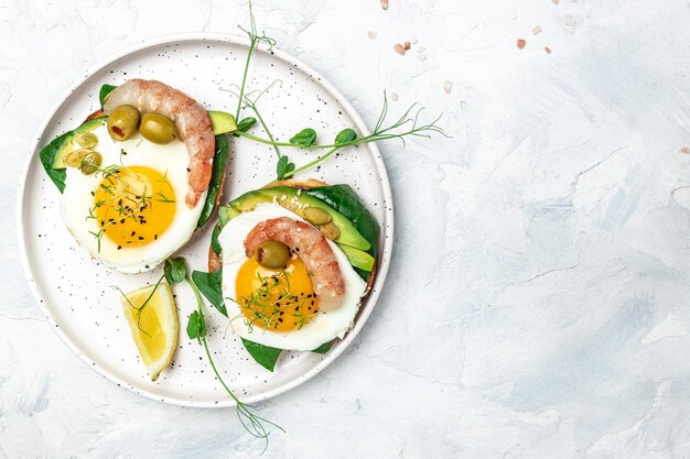 통밀빵을 곁들인 토스트 부드러운 달걀 시금치 아보카도 새우를 배경으로 케토제닉 아침 슈퍼푸드 개념 건강한 깨끗한 식습관