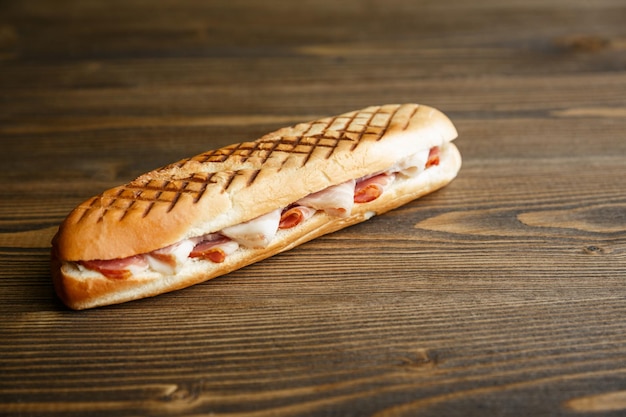 Toasted baguette sandwich with ham on a wooden background