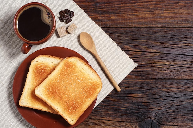 Toasted bread and cup of hot coffee on rustic wooden table. Top view