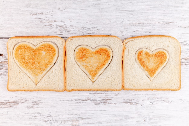 Toasted bread hearts on wooden table, concept of breakfast in happy family