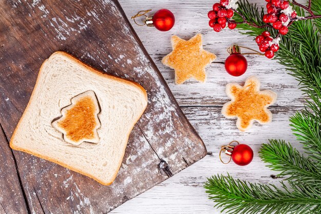 Toasted bread shaped like fir tree and snowflake on rustic wooden cutting board