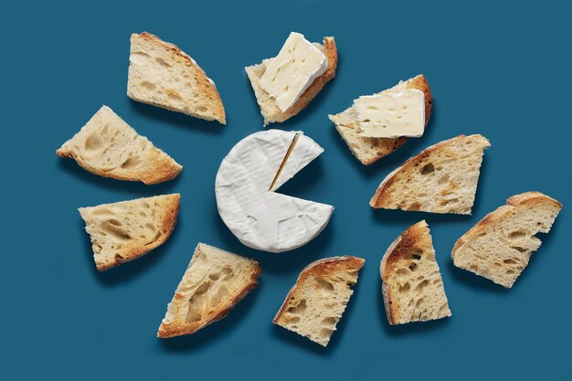 Toasted bread slices and brie cheese on dark blue background, top view