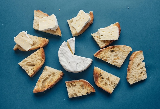 Toasted bread slices and brie cheese on dark blue background, top view