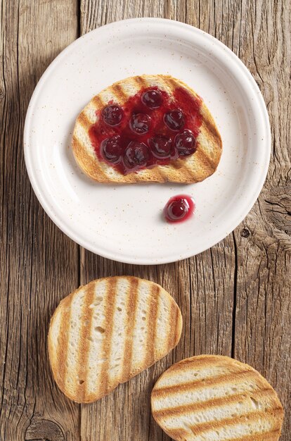 Toasted bread with cherry jam in plate on the table