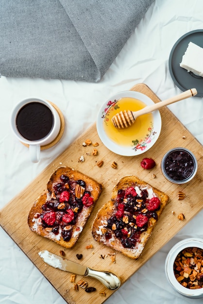 Toasted bread with honey, cream cheese, red fruit jam and coffee