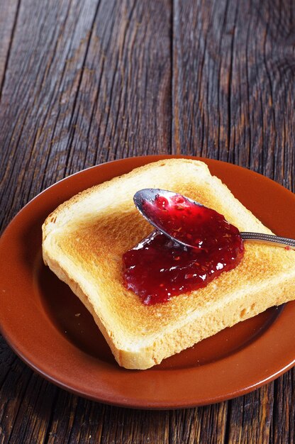 Toasted bread with jam on rustic wooden table